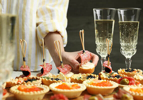 Woman taking tasty canape at table, closeup