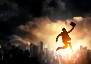 Silhouette of businessman jumping in air against modern cityscape. Mixed media
